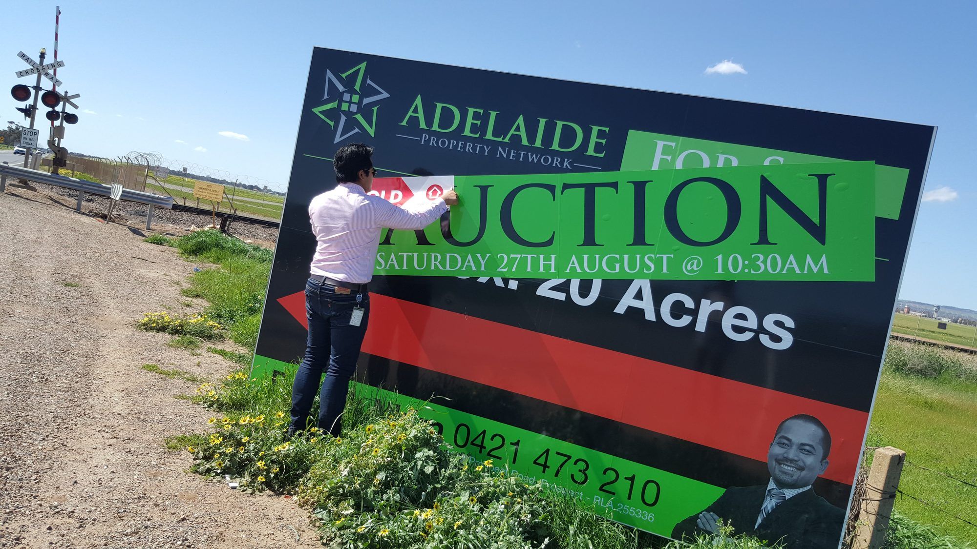 A SOLD sticker going up on an Adelaide Property Network auction sign